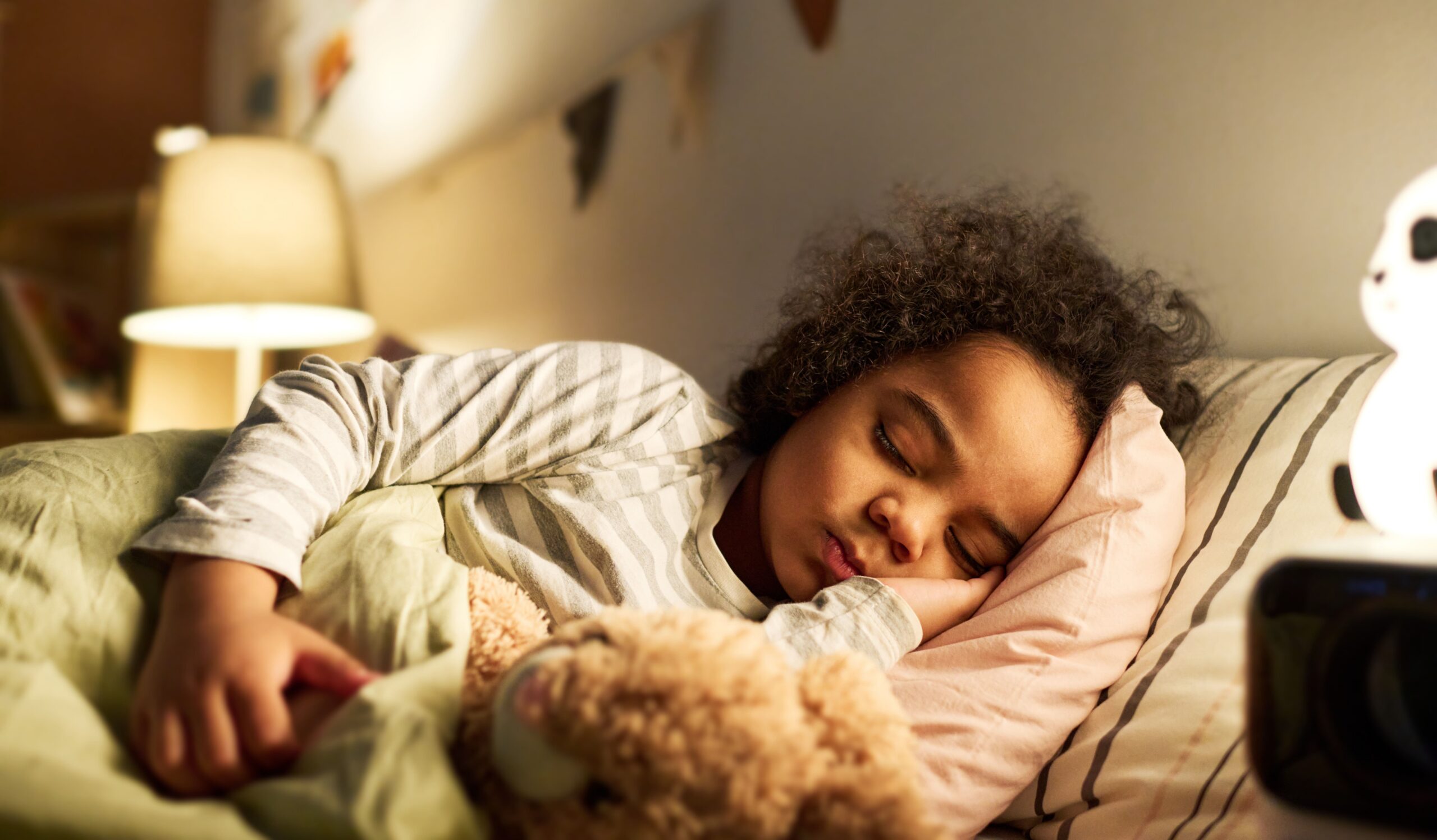 Petite fille qui dort paisiblement dans un lit pour enfant avec son doudou