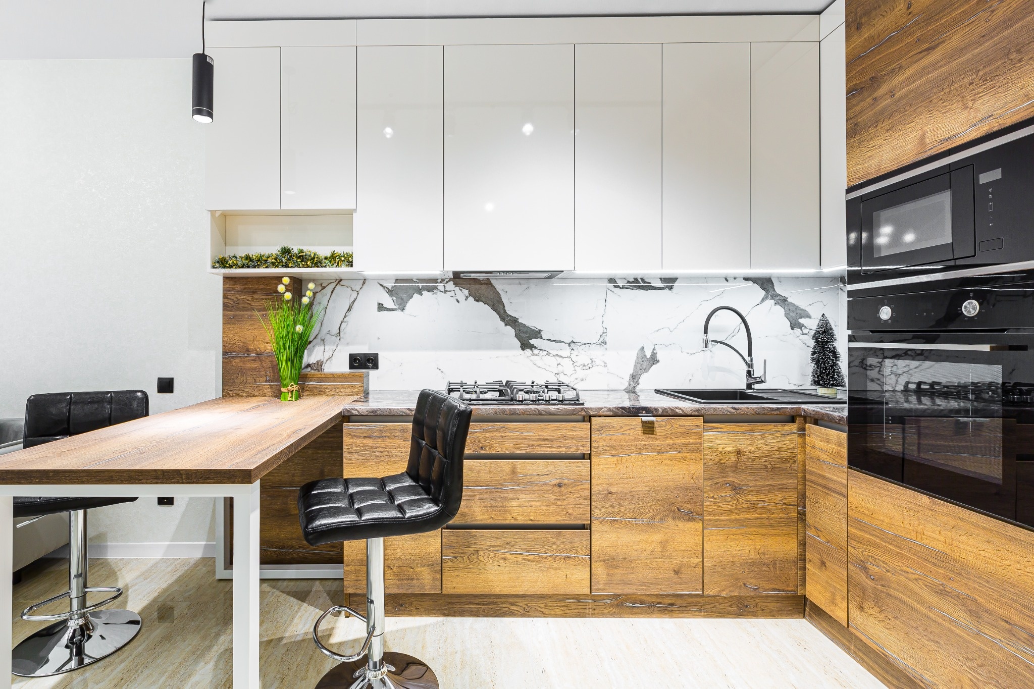 Photo d'une petite cuisine moderne et lumineuse en chêne et blanc laqué, illustrant une optimisation totale de l'espace avec des rangements ingénieux du sol au plafond.