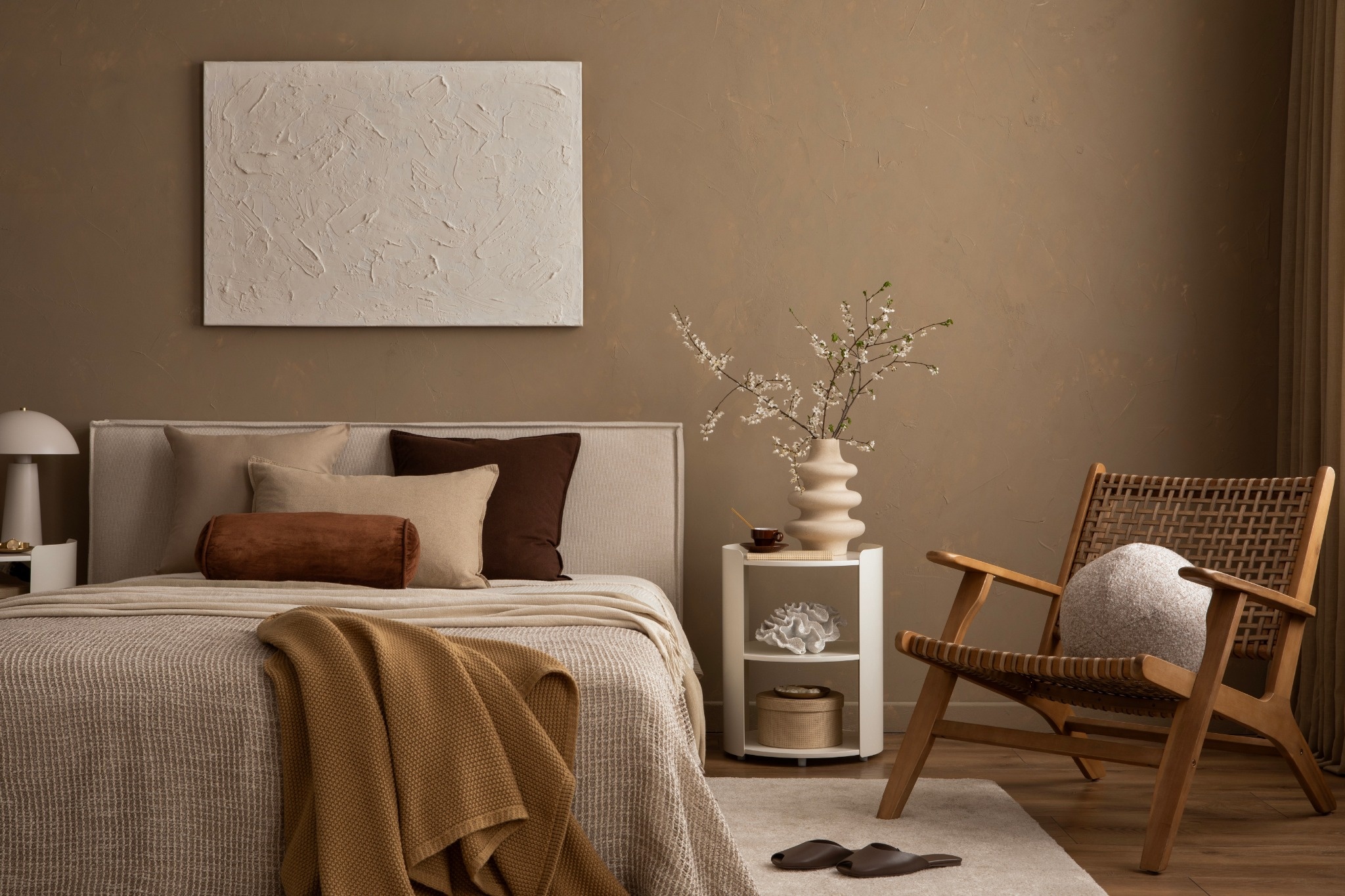Décoration de chambre à coucher fraîche et épurée avec draps en lin froissé de couleur naturelle et fauteuil en rotin tressé.