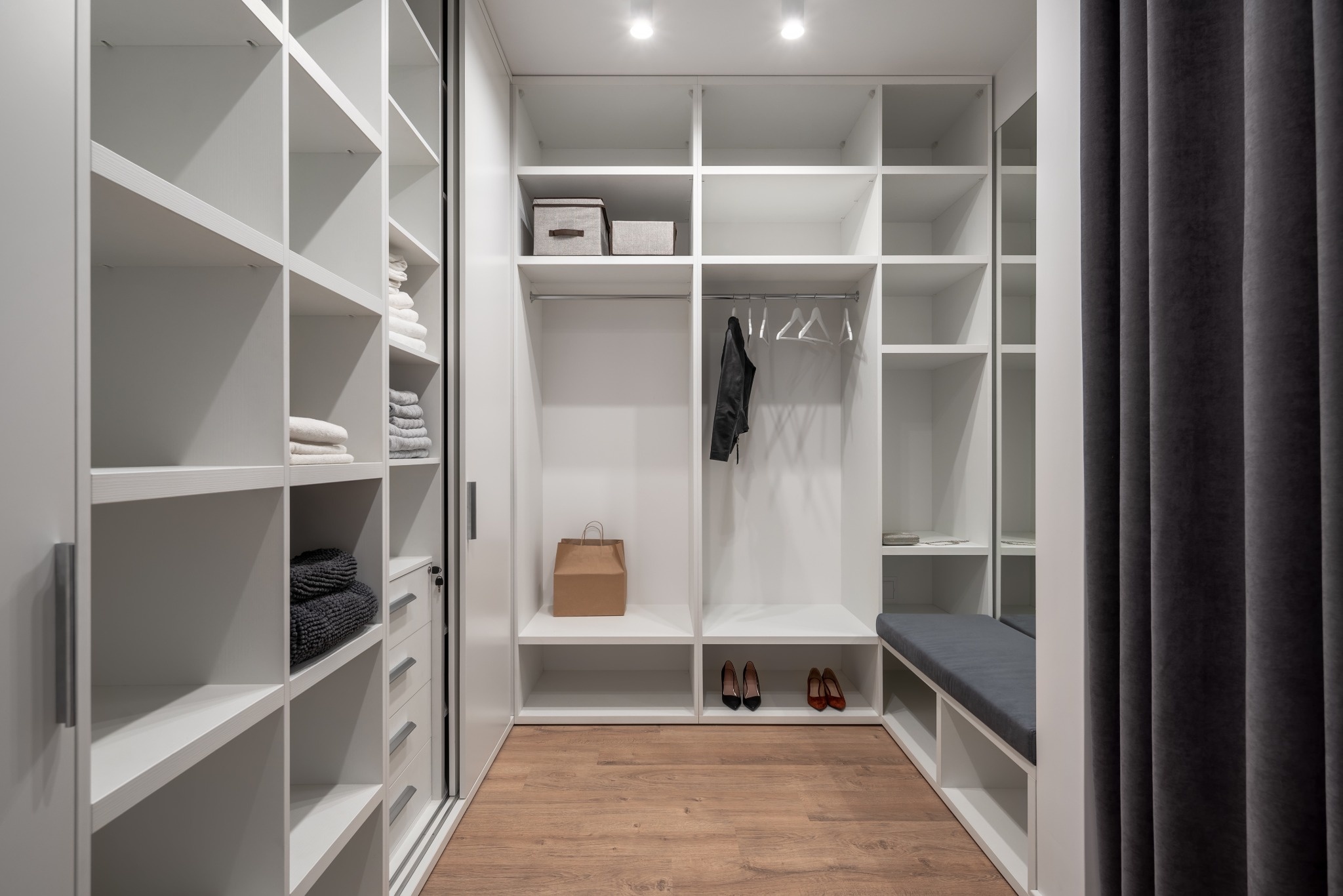Vue d'ensemble d'un grand dressing moderne et ordonné avec étagères blanches et penderies.