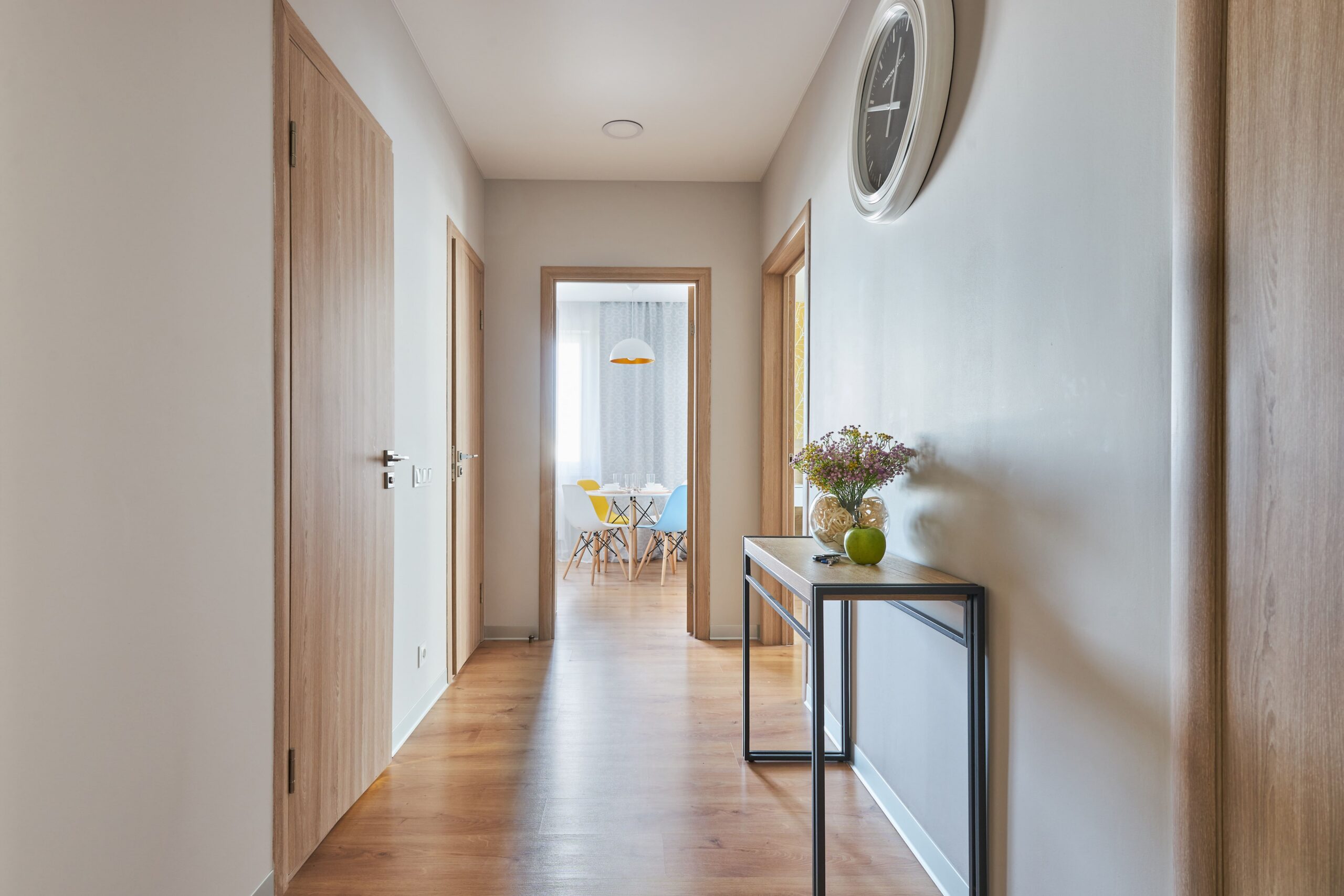 Petite entrée et couloir étroit lumineux avec sol en parquet bois clair et console fine.
