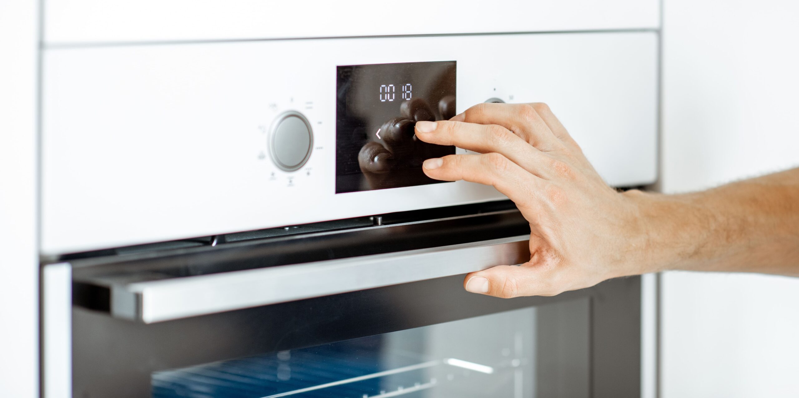 Main réglant un pictogramme de cuisson sur l'écran tactile d'un four encastrable