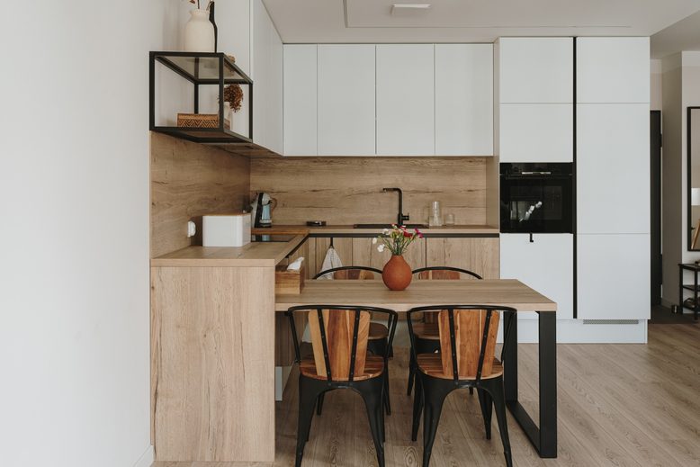 Cuisine lumineuse avec meubles en bois clair, placards blancs et table à manger en bois.